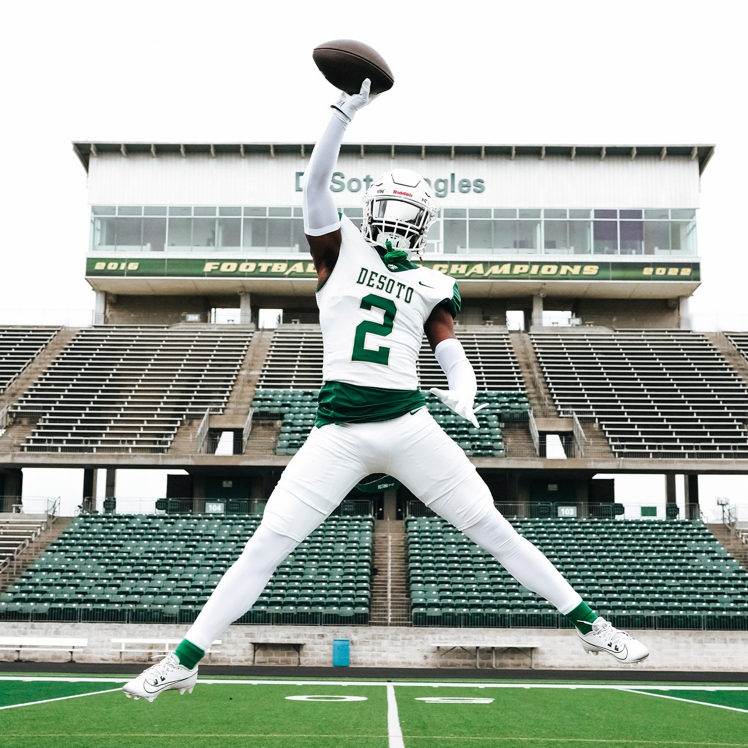 High School Football Player Wearing NXTRND Crew Mid Cut Padded Socks Dark Green and Compression Arm Sleeves White