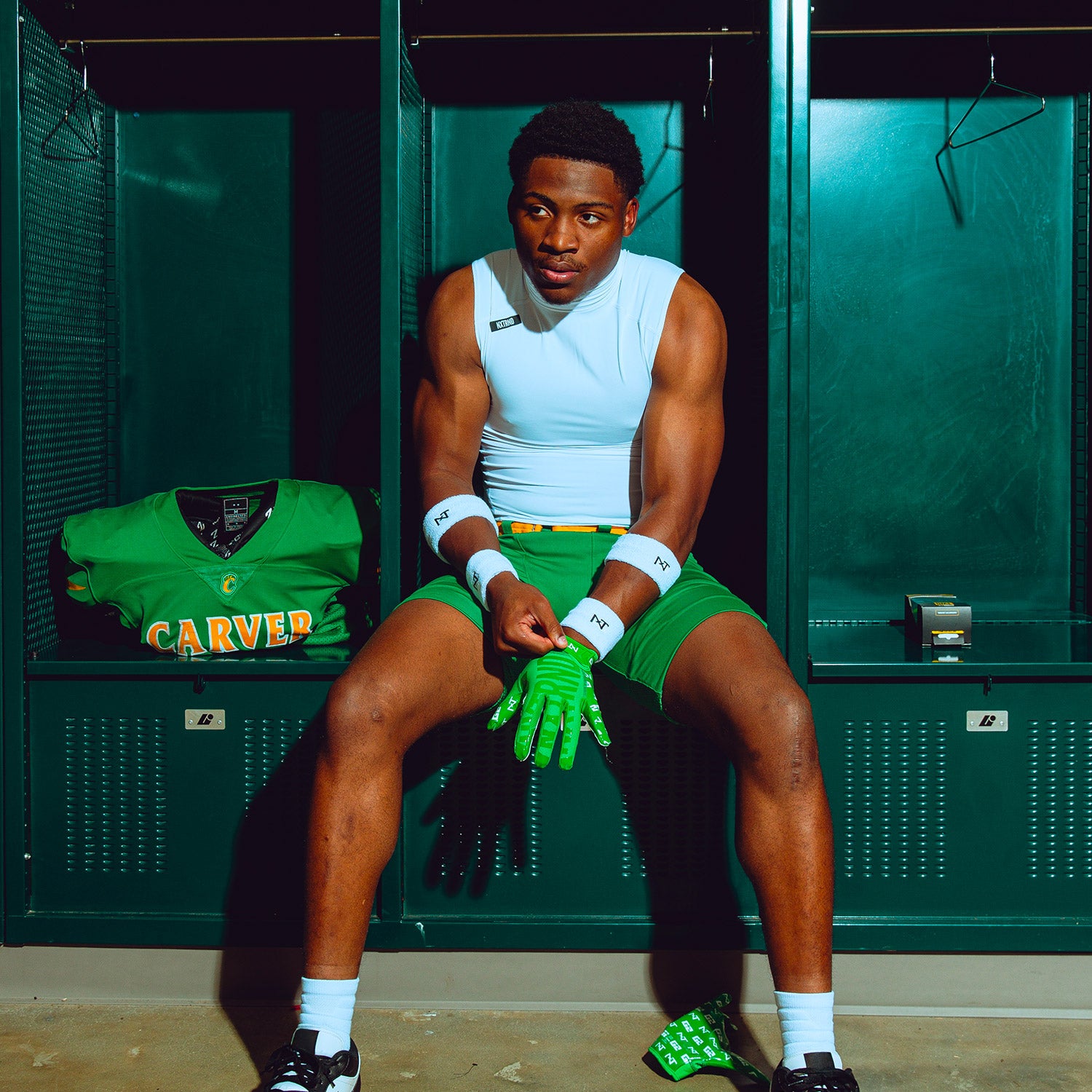 High School Football Player in Locker Room Wearing NXTRND G2 Pro Football Gloves Green and Core Sleeveless Mock Turtleneck Compression Shirt