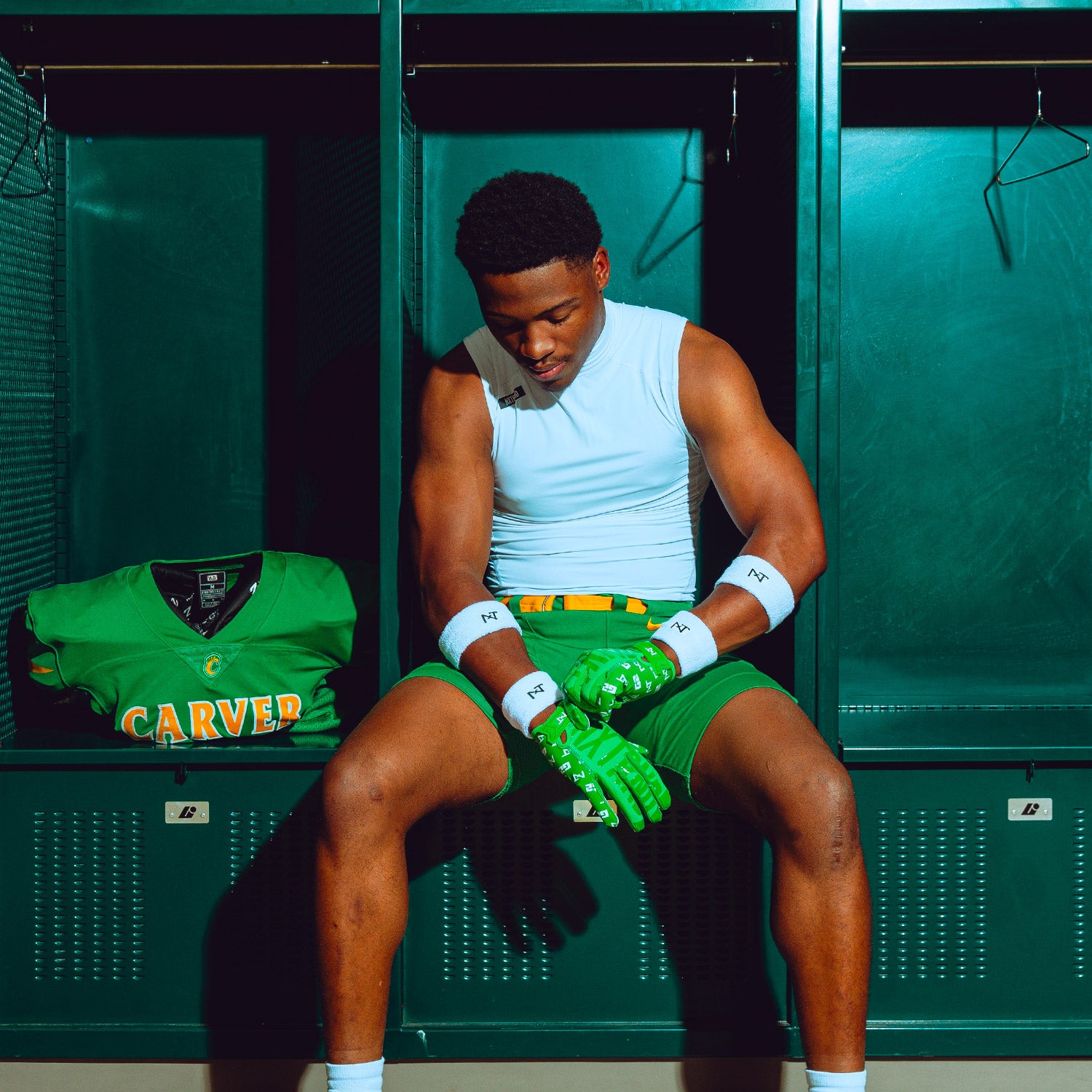 High School Football Player in Locker Room Wearing NXTRND G2 Pro Football Gloves Green and Core Sleeveless Mock Turtleneck Compression Shirt