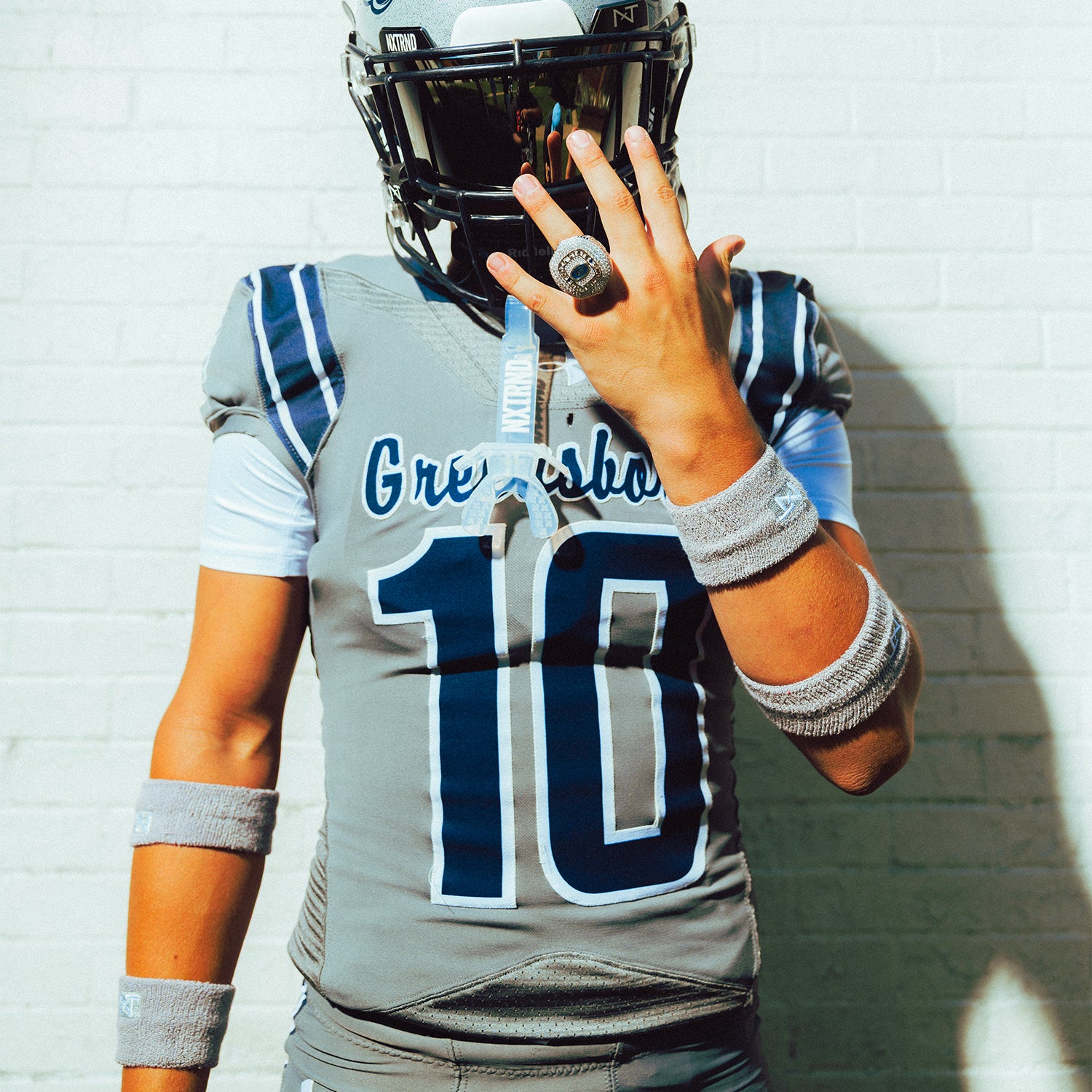 High School Football Player Wearing NXTRND Wrist Band Grey and TWO Football Mouthguard Transparent