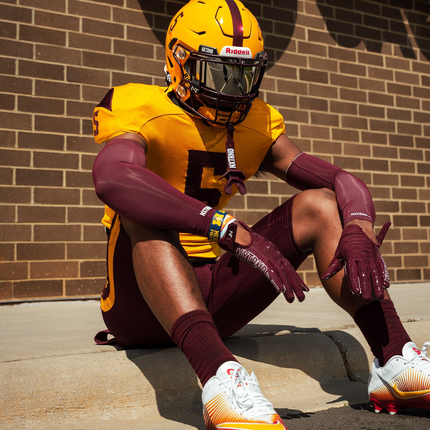 High School Football Player Wearing NXTRND Crew Mid Cut Padded Socks Maroon and Compression Arm Sleeves Maroon