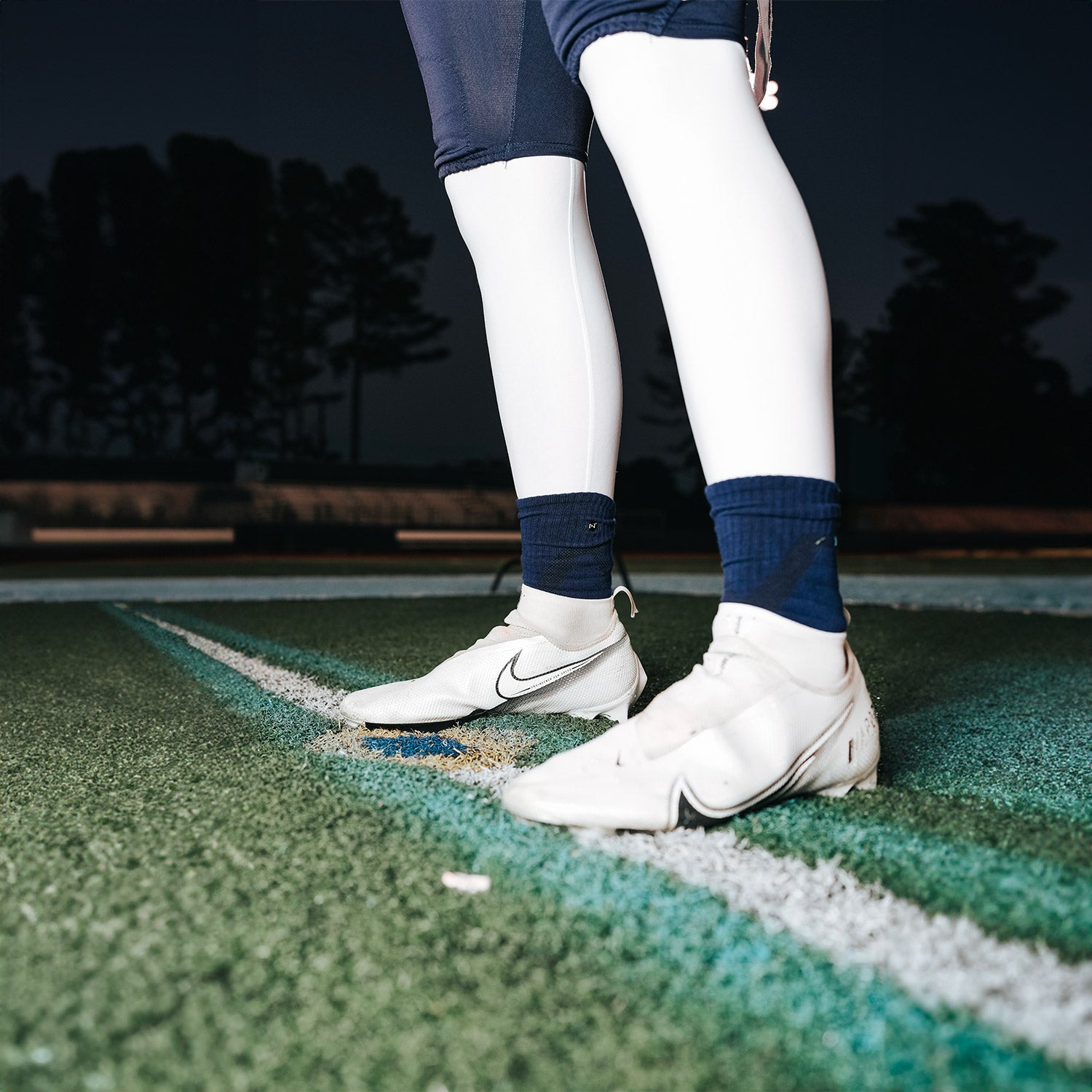 High School Football Player Wearing NXTRND Crew Mid Cut Padded Socks Navy Blue and Core Compression Pants White