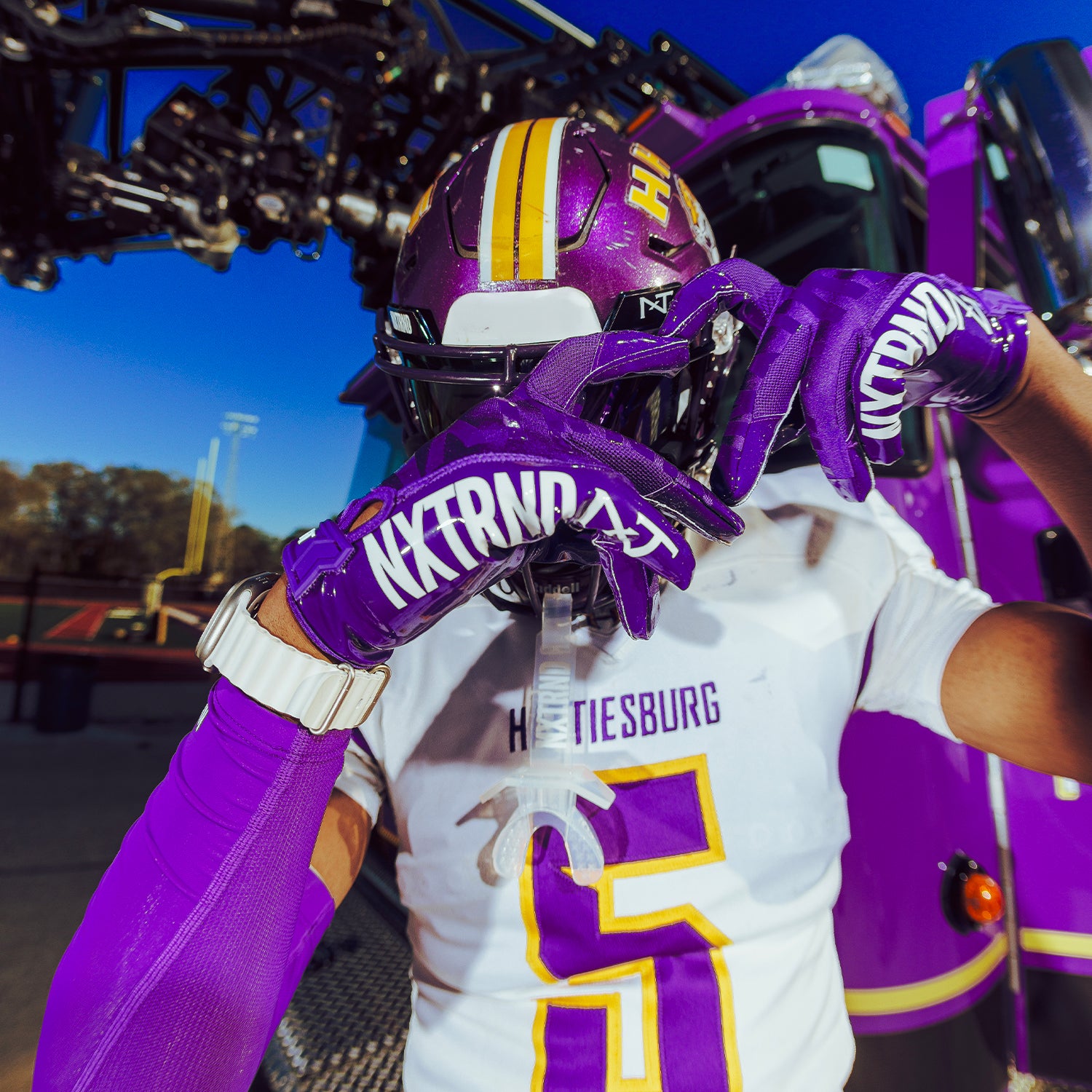 High School Football Player Outdoors Wearing NXTRND G1 Pro Football Gloves Purple and TWO Mouthguard Transparent